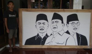 Foto : Ja'far Labib bersama hasil karyanya, lukisan tiga wajah Calon Presiden (Capres) 2024 (Sumber : Dok. Pribadi)