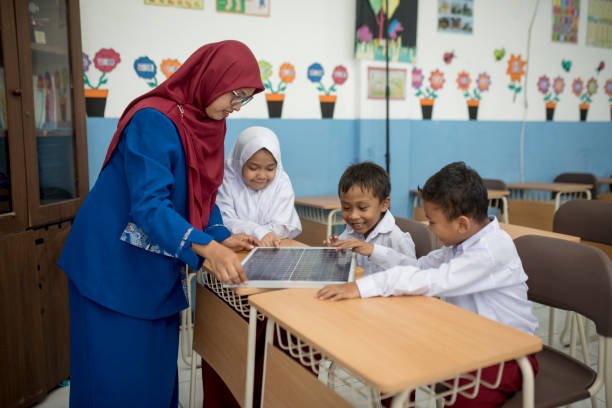 Students study solar panels with teacher in class